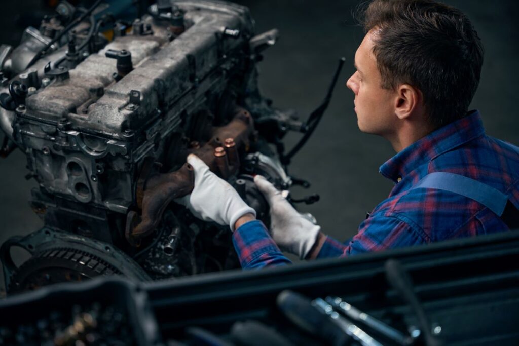 Mechanic inspecting a high-mileage car engine in a workshop