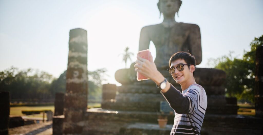 Traveler holding phone taking selfie with iconic landmark in background